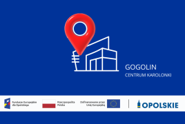Grafika promocyjna na granatowym tle. W centrum znajduje się biały kontur nowoczesnego budynku z dużym czerwonym znacznikiem lokalizacji nad nim. Po prawej widnieje napis „GOGOLIN” oraz „CENTRUM KAROLONKI”. Na dole umieszczono pasek z logotypami Funduszy Europejskich dla Opolskiego, Rzeczypospolitej Polskiej, Unii Europejskiej i marki Opolskie.